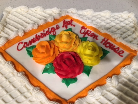 Closeup of sheet cake decorated with red and orange flowers for grand opening of new Cambridge Community Room