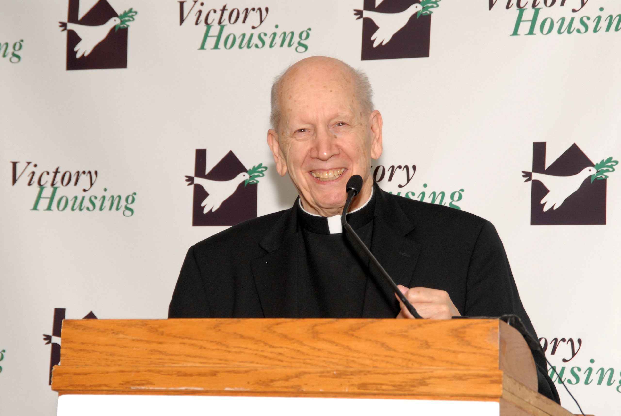 Victory Housing founding father Monsignor Ralph J. Kuehner stands at podium to receive Washingtonian of the Year Award