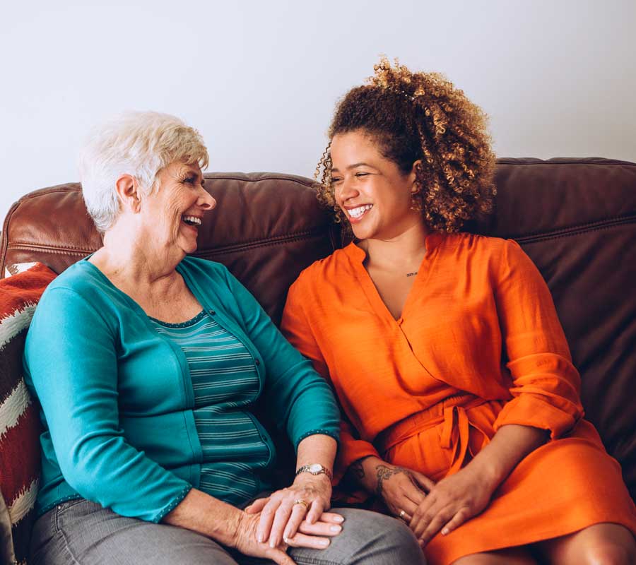 senior laughing with her granddaughter on the couch